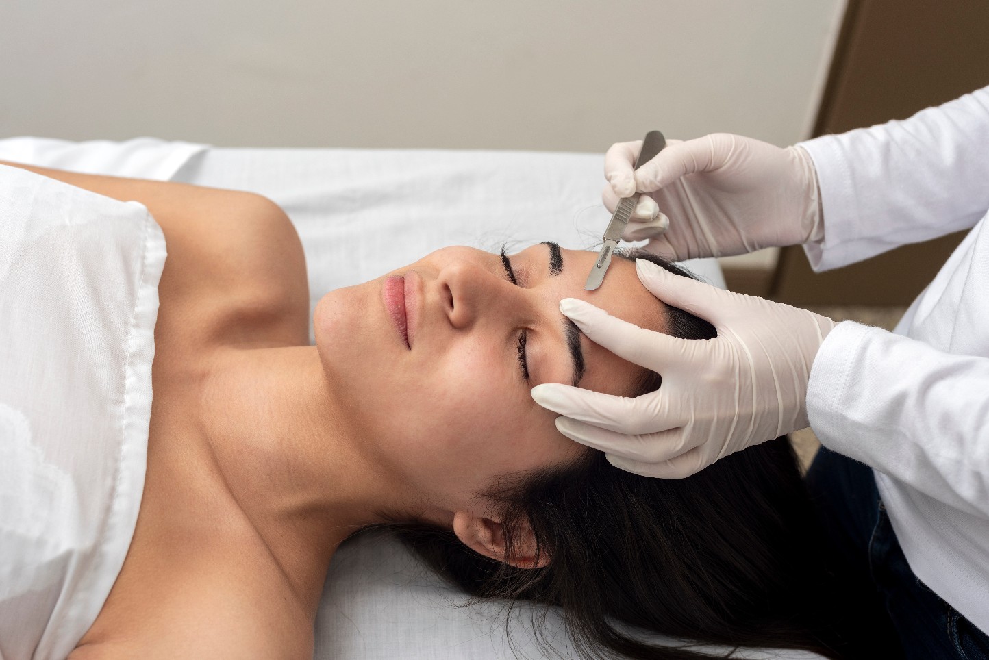young woman on a table in a beauty center performing a beauty treatment for facial skin with the dermaplaning technique